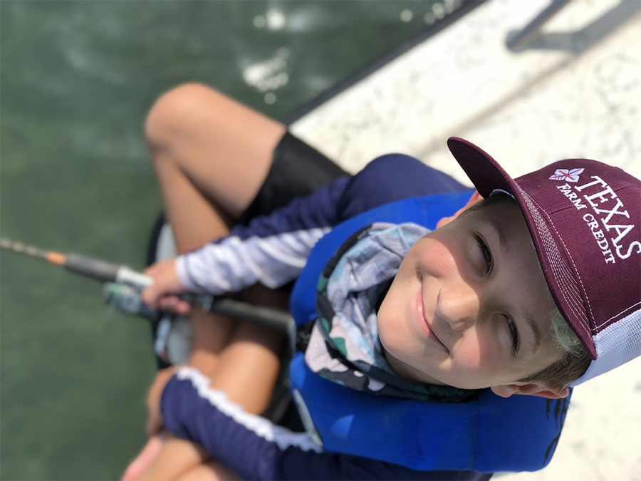 Photo of a young boy fishing and smiling for the camera